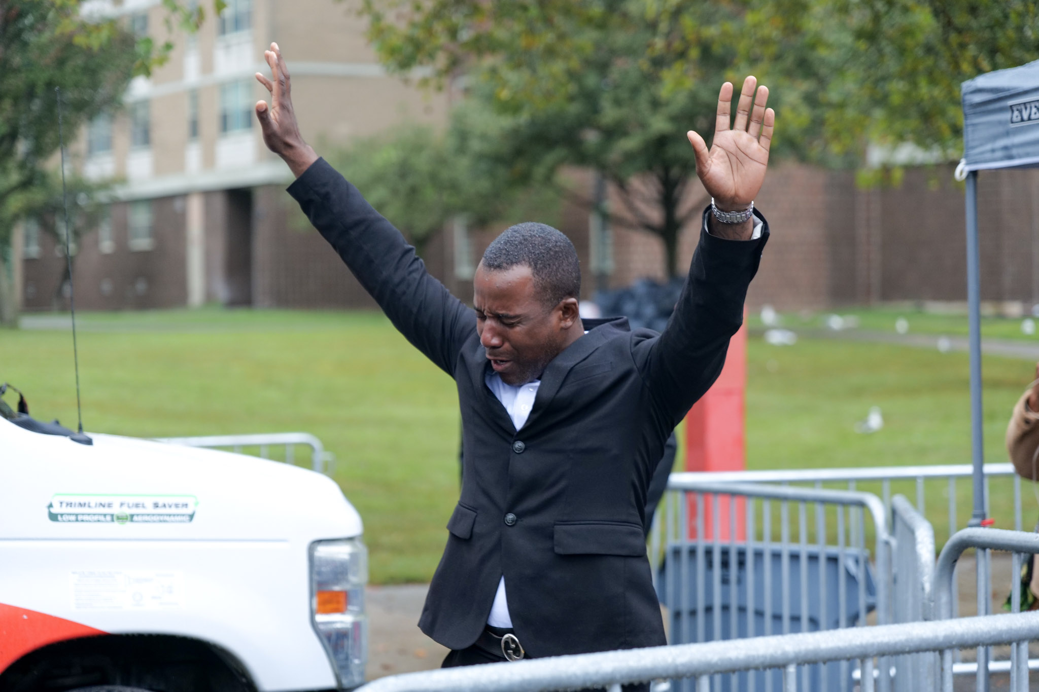 A man raises both hands while worshipping in the rain during the gospel and jazz finale of the East New York Concert + Wellness Series.